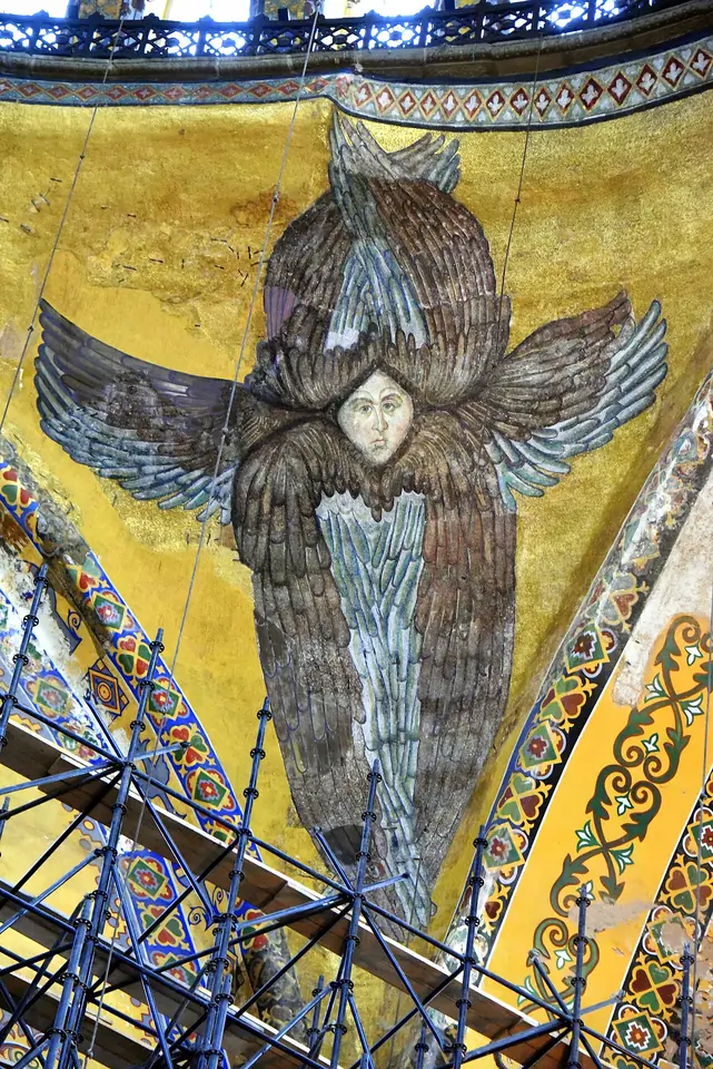 Byzantine gold mosaic of a seraph whose six gray-blue wings wrap around a small calm human face