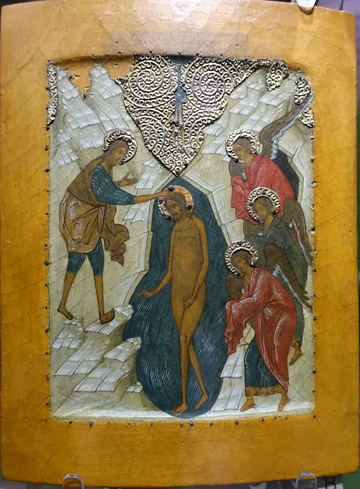 Russian icon of Christ standing in the dark blue Jordan between steep rocks, John on the left reaching to his head, three angels on the right with covered hands, and rays descending from a half-circle of heaven above