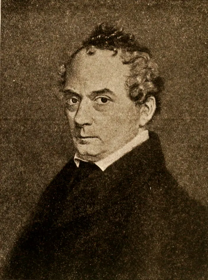 Black-and-white portrait of a middle-aged man with dark curly hair and a high white collar under a dark coat