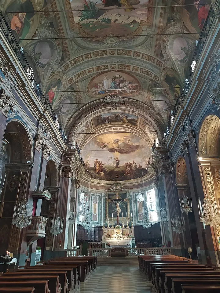 The painted nave of Sassello's parish church, with frescoed vaults, gilded side altars and rows of wooden pews leading to the high altar