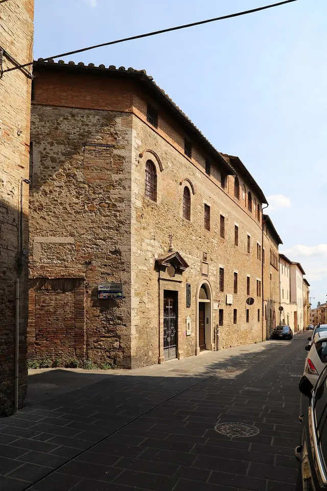 A long medieval brick and stone convent building along a quiet sloping street in Perugia