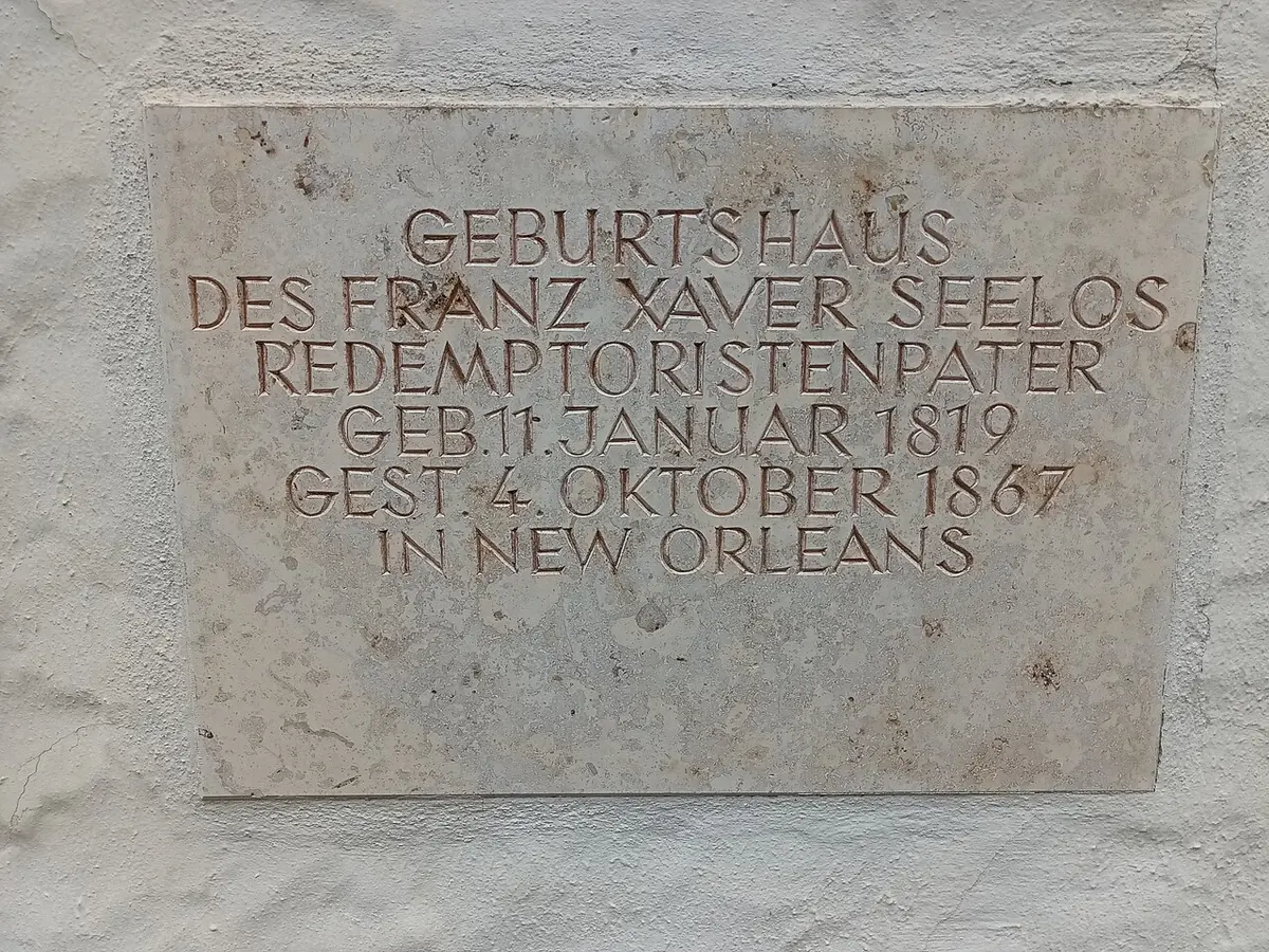 A stone plaque on a white wall with German lettering marking the birthplace of the Redemptorist Franz Xaver Seelos, born January 11, 1819, died October 4, 1867, in New Orleans