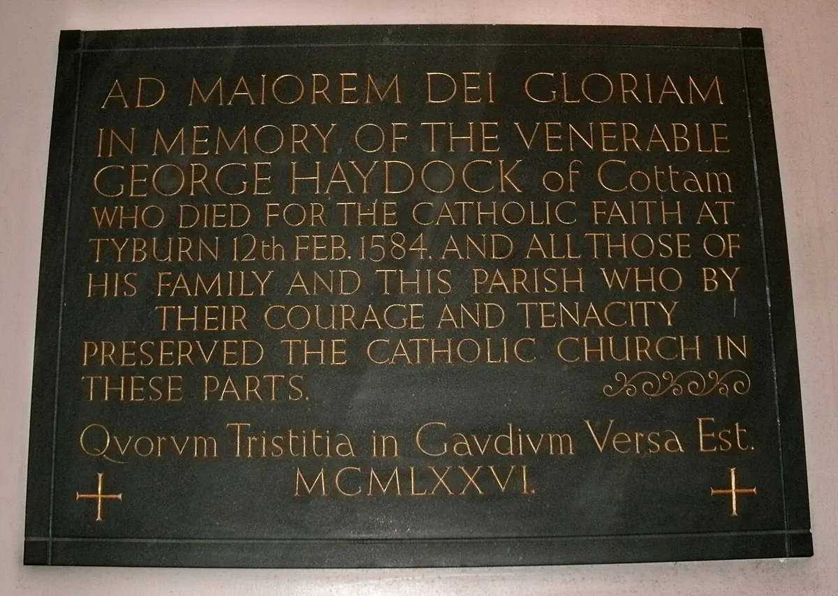 A dark green plaque with gold lettering in memory of the Venerable George Haydock of Cottam, who died for the Catholic faith at Tyburn on February 12, 1584