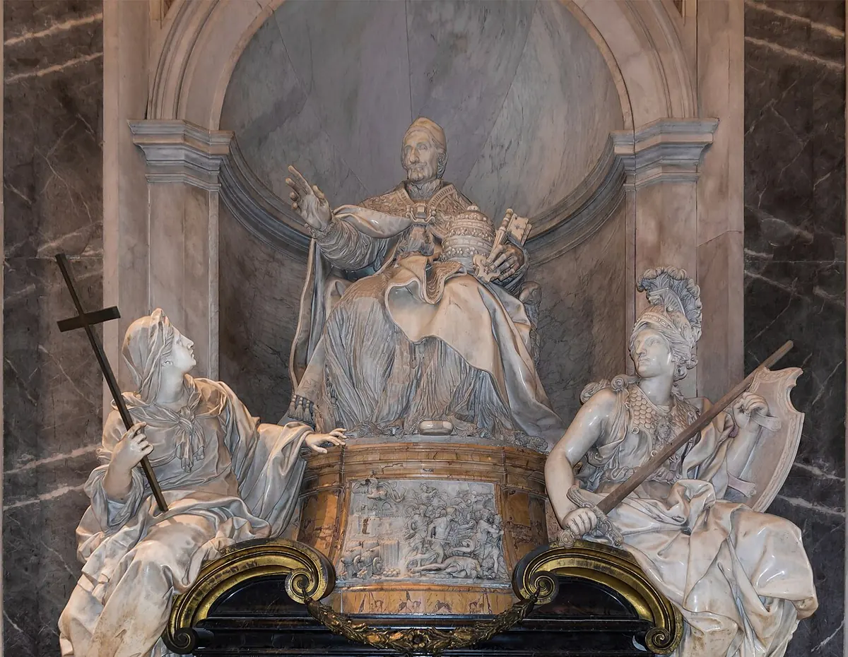 White marble monument with a seated pope raising his hand above a gilded sarcophagus, flanked by two marble women, one holding a cross and the other a sword