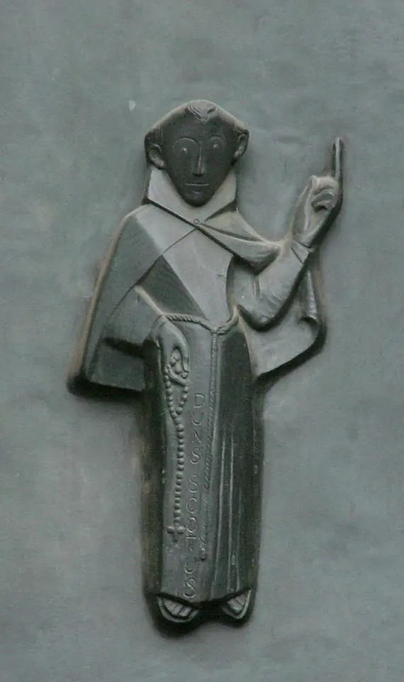 Stylized bronze relief of a hooded friar holding a rosary and raising one finger, set into a smooth gray door panel
