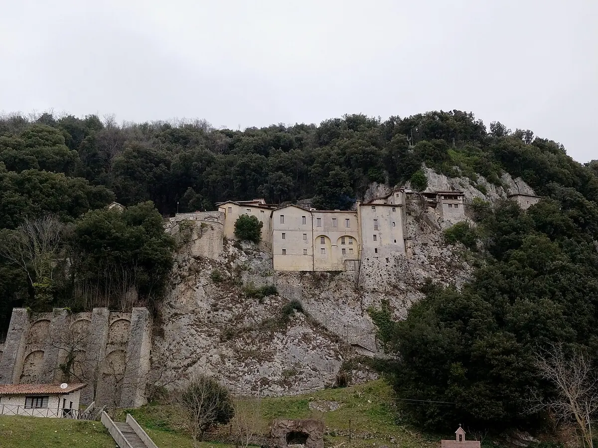 The small stone friary of Greccio clinging to a rocky cliff above a wooded valley