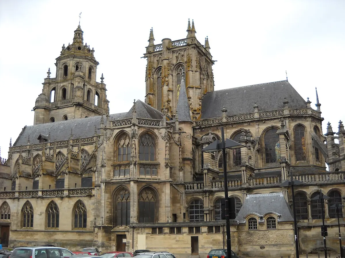 A large Gothic church of pale stone with two ornate towers and a long row of flying buttresses