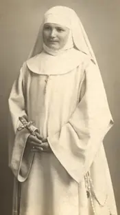 Old sepia photograph of a young sister in a white habit, white veil and wimple, standing with her hands folded