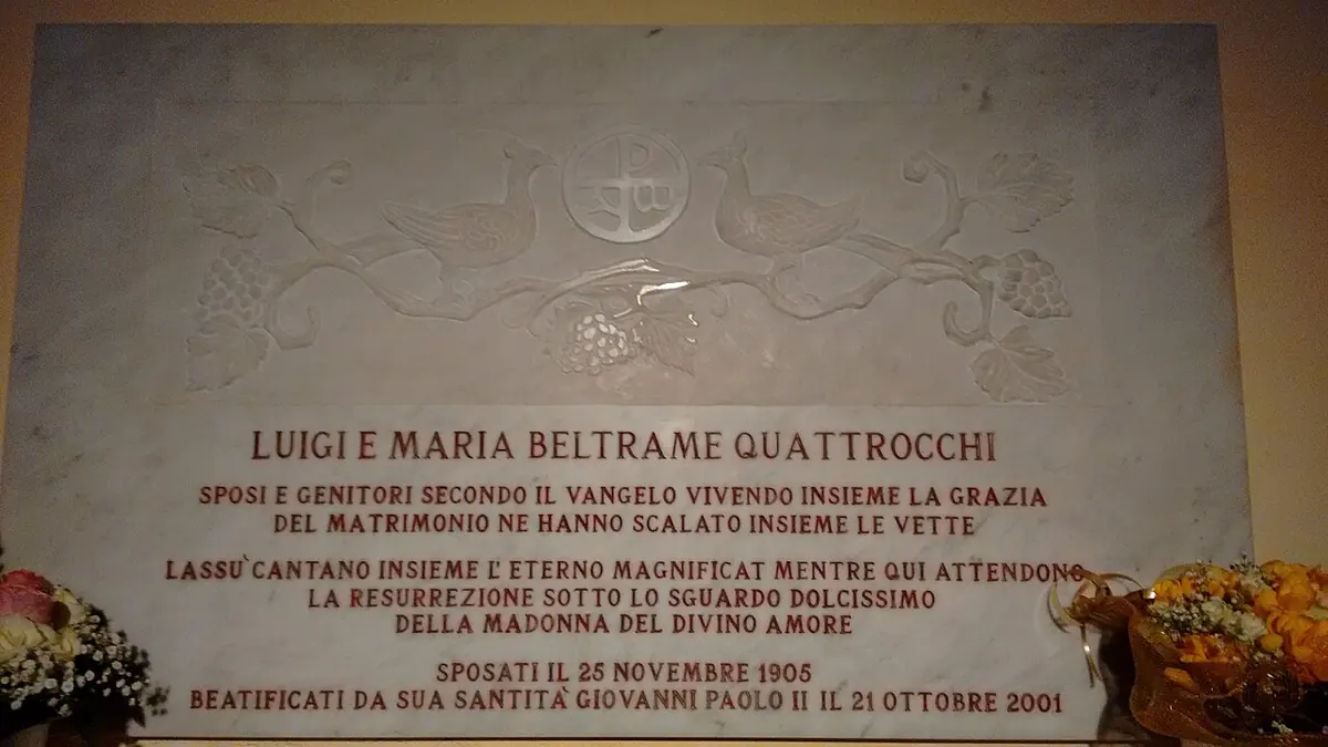 A white marble plaque carved with vines and inscribed in Italian with the names of Luigi and Maria Beltrame Quattrocchi, their wedding date and their beatification