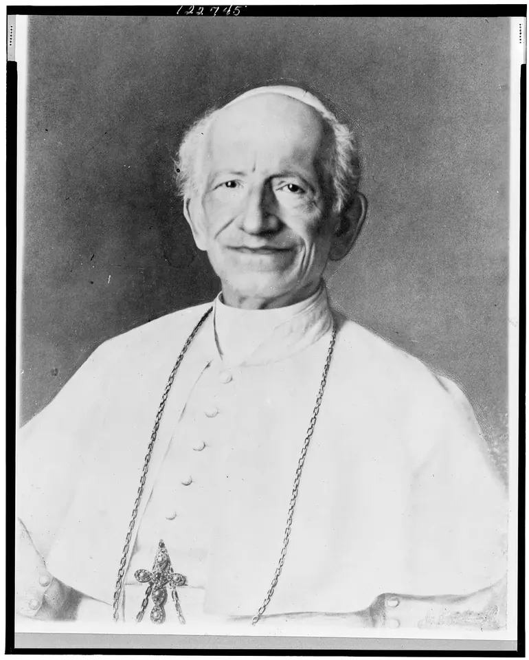 Old black-and-white photograph of an elderly smiling pope in a white cassock and skullcap with a pectoral cross