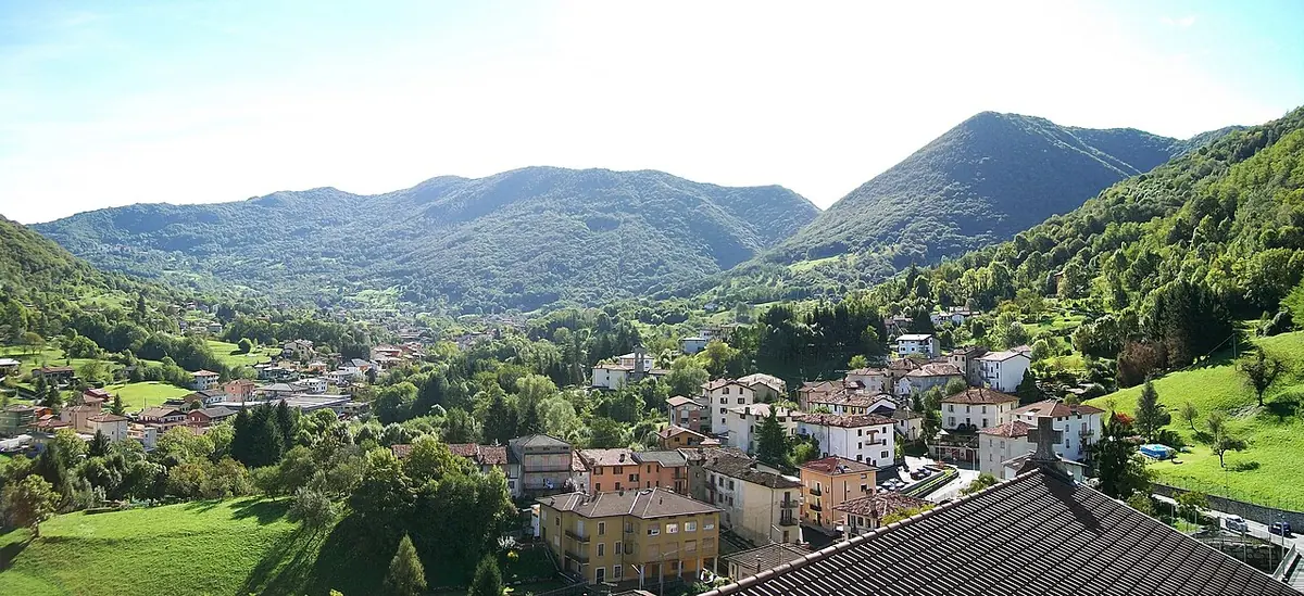 Wide view of the village of Fiobbio among green wooded hills in the Luio valley near Bergamo