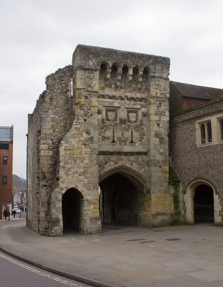 The Westgate of Winchester, a medieval stone gatehouse with a dark arch, small square windows and carved shields on its face