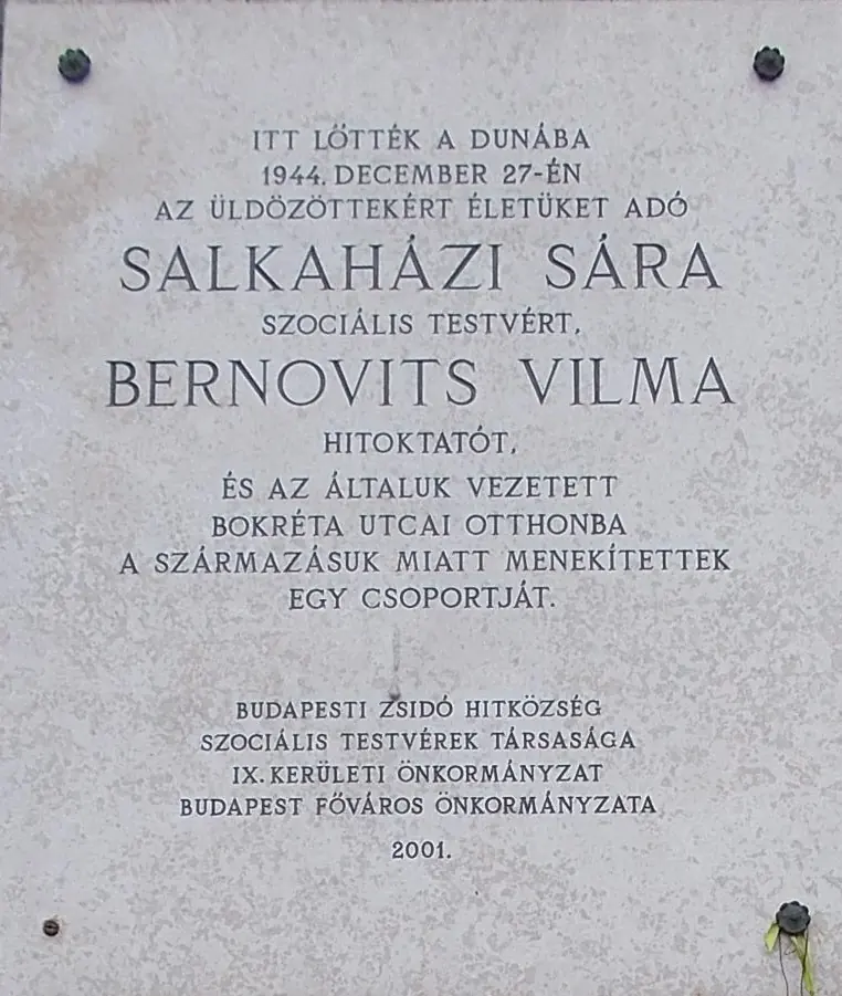 White stone plaque in Hungarian stating that Sára Salkaházi and Vilma Bernovits were shot into the Danube here on December 27, 1944, placed in 2001 by the Jewish community of Budapest and others