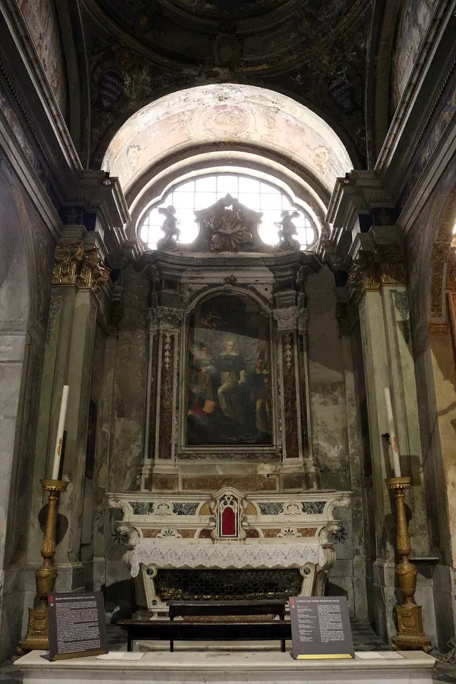 A marble side chapel with a painted altarpiece of the arrival of Blessed Sebastian at the convent, above an altar and a glass urn