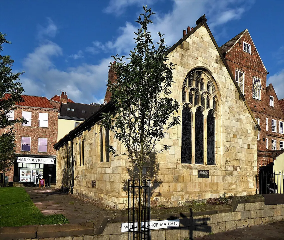 Small stone Gothic building with a large traceried window at the end of the Pavement in York, built from the remains of the demolished church of St Crux