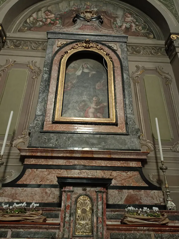 A marble side altar in pink and gray stone with a gilded frame holding a seventeenth-century painting of Blessed Veronica