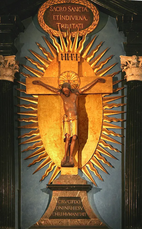 Large carved wooden figure of the dead Christ on a cross, set before a golden sunburst frame between marble columns, with Latin inscriptions above and below
