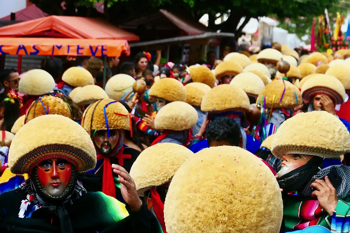 Una multitud de parachicos con máscaras de madera, monteras de ixtle amarillas y sarapes de colores llena una calle de Chiapa de Corzo