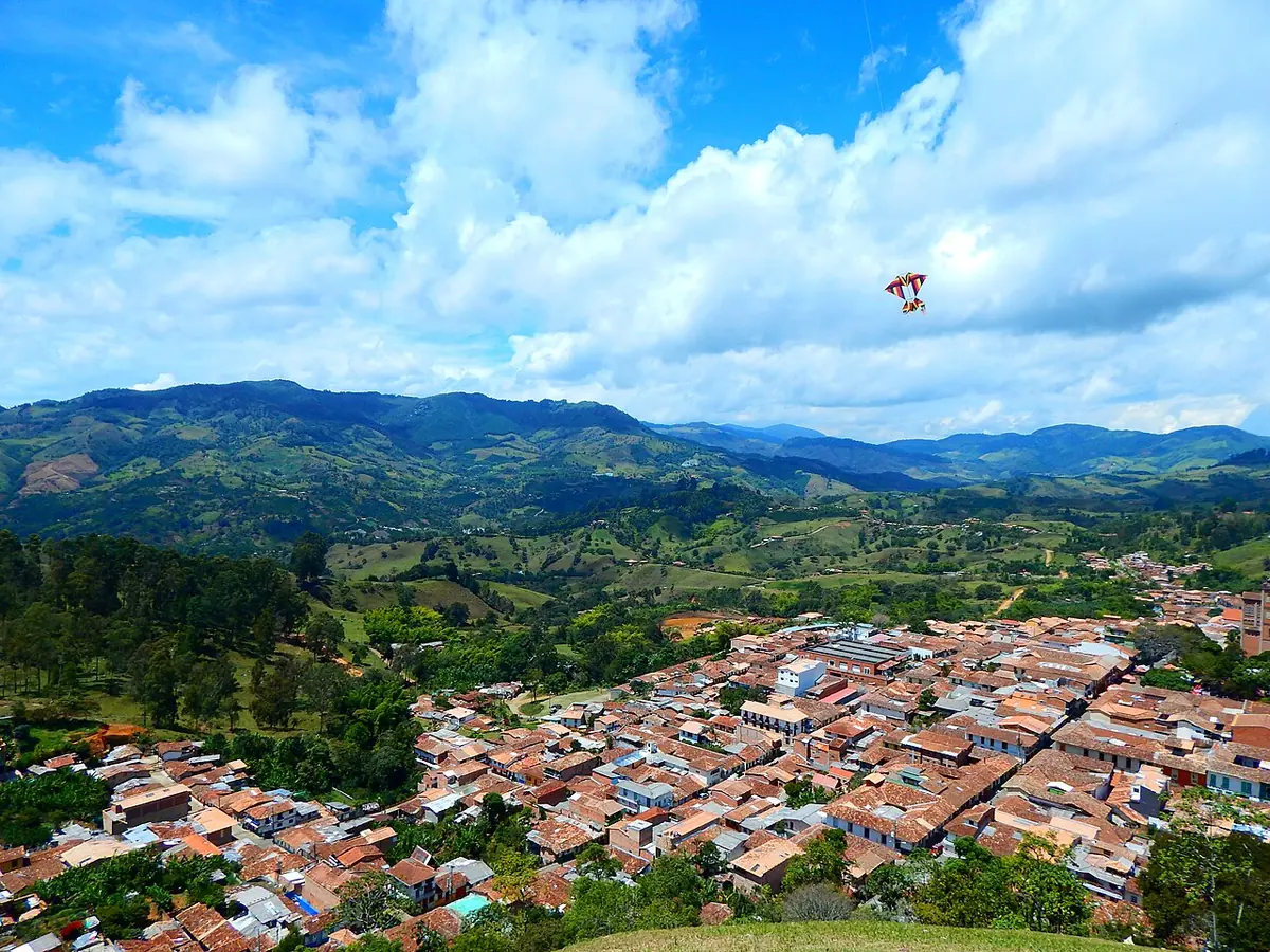 El pueblo de Jericó visto desde un cerro, con sus techos de teja entre montañas verdes bajo un cielo con nubes blancas