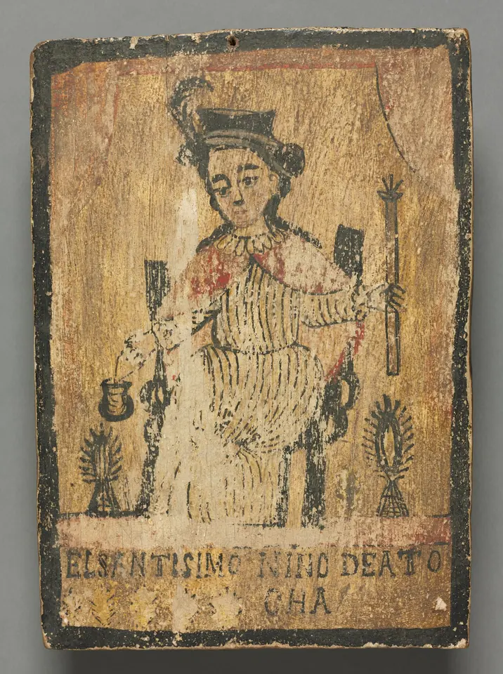 Antiguo retablo pintado al óleo sobre una tabla gastada que muestra al Niño de Atocha sentado en una silla, con sombrero de pluma y capa roja, un bastón en una mano y una canastilla en la otra, entre dos candeleros