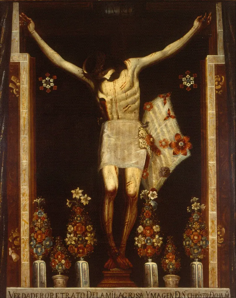 Pintura al óleo de un Cristo crucificado de piel clara y paño blanco, con la cabeza caída, dentro de un nicho oscuro, con jarrones de flores a los pies y una inscripción al pie del lienzo