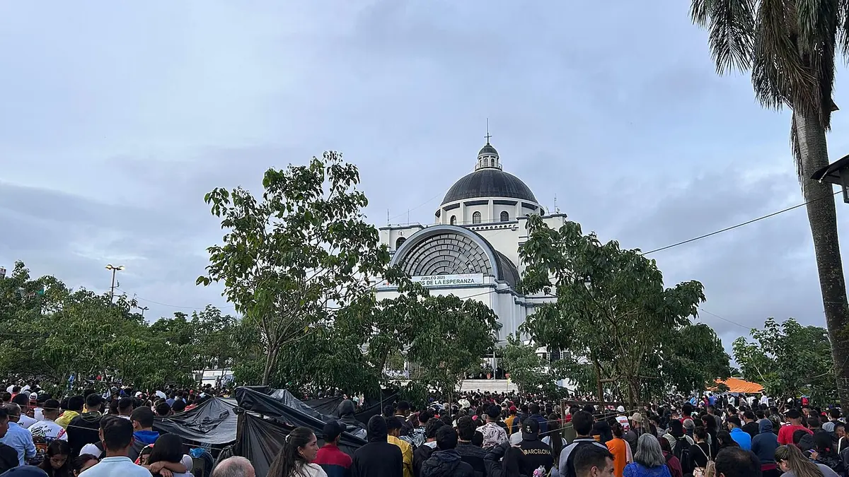 Una multitud de peregrinos llena la explanada ante la basílica de Caacupé, cuya cúpula se ve detrás de los árboles, el día de la fiesta