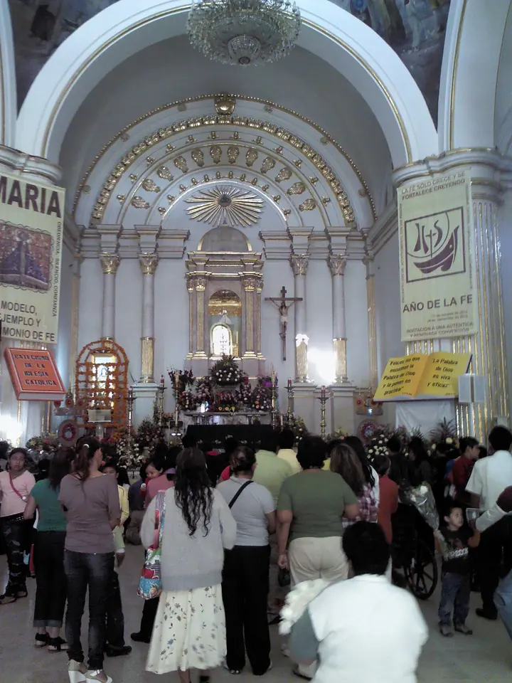 Interior blanco y dorado del santuario de Juquila lleno de peregrinos que avanzan hacia el altar mayor, donde se venera la pequeña imagen