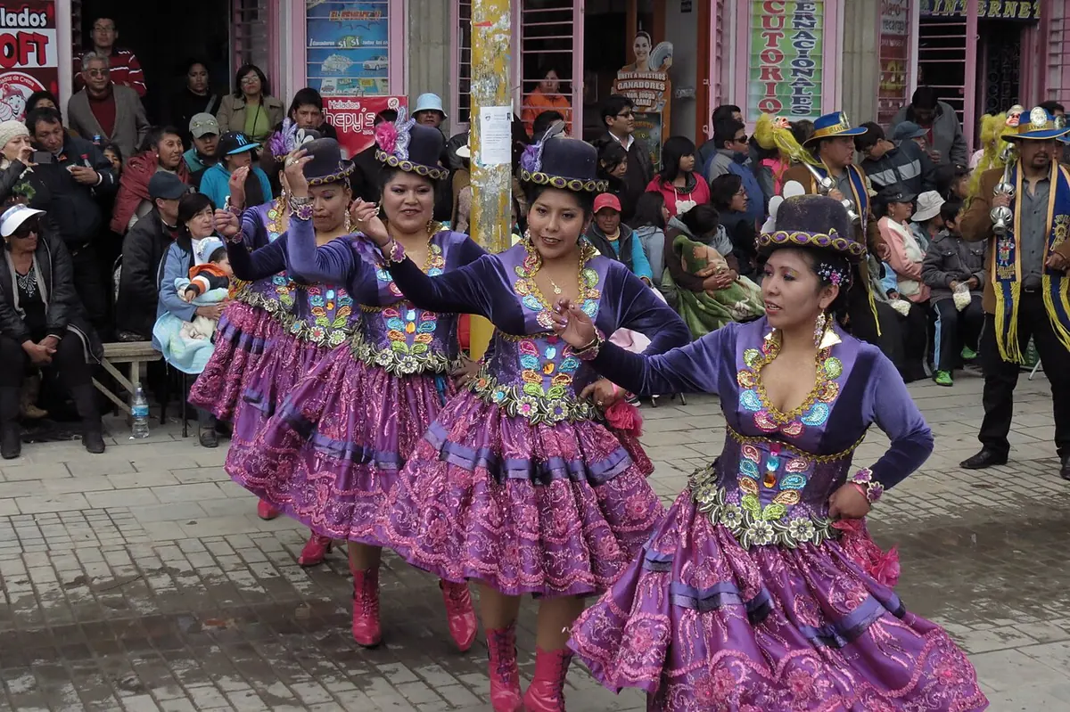 Bailarinas de morenada con polleras moradas y sombreros bordados danzan por una calle de Puno ante el público, durante la fiesta de la Candelaria