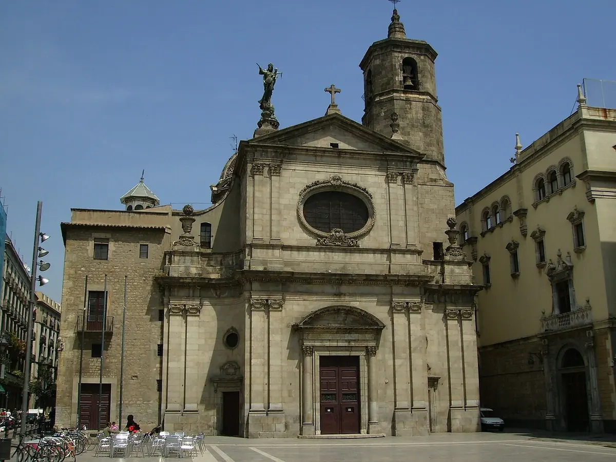 Fachada barroca de piedra de la basílica de la Mercè de Barcelona, con su campanario y, en lo alto de la cúpula, una estatua de la Virgen