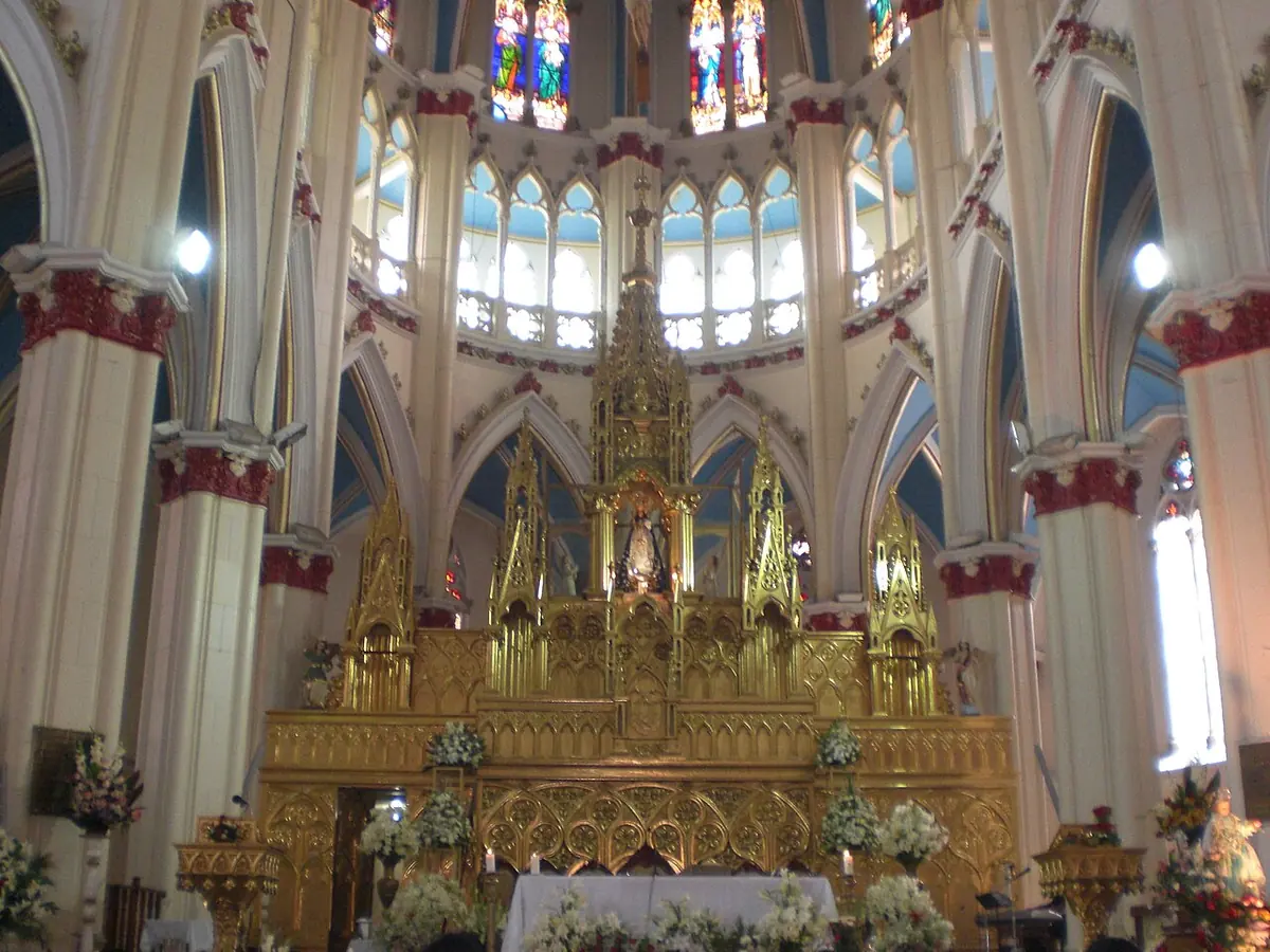 El altar mayor dorado de la basílica de El Cisne, de estilo neogótico, con columnas pintadas de blanco y rojo y vitrales arriba, donde se venera la imagen de la Virgen
