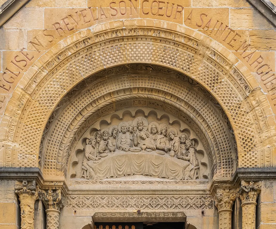 Carved stone doorway arch of a chapel with a relief of the Last Supper and an inscription in French along the outer arch