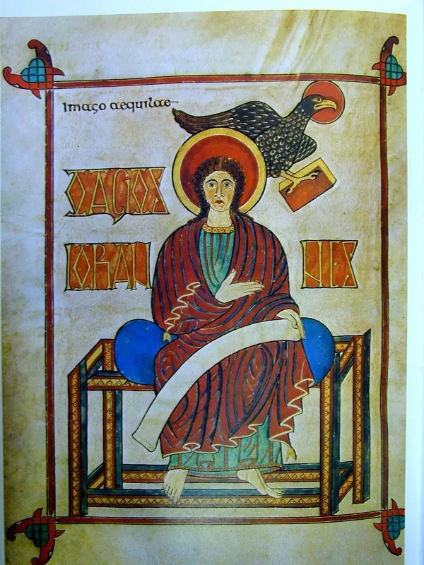 Anglo-Saxon manuscript painting of St. John seated frontally in a red robe on a cushioned bench holding a scroll, an eagle holding a book above his halo