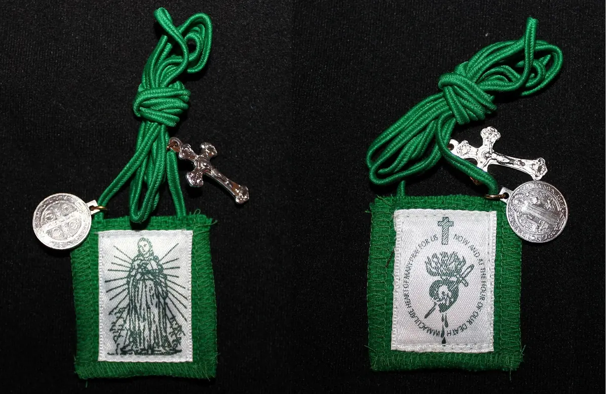 Front and back of a green felt scapular on a coiled green cord with a small medal and crucifix attached, one side printed with the standing Virgin and the other with a pierced heart and an oval prayer