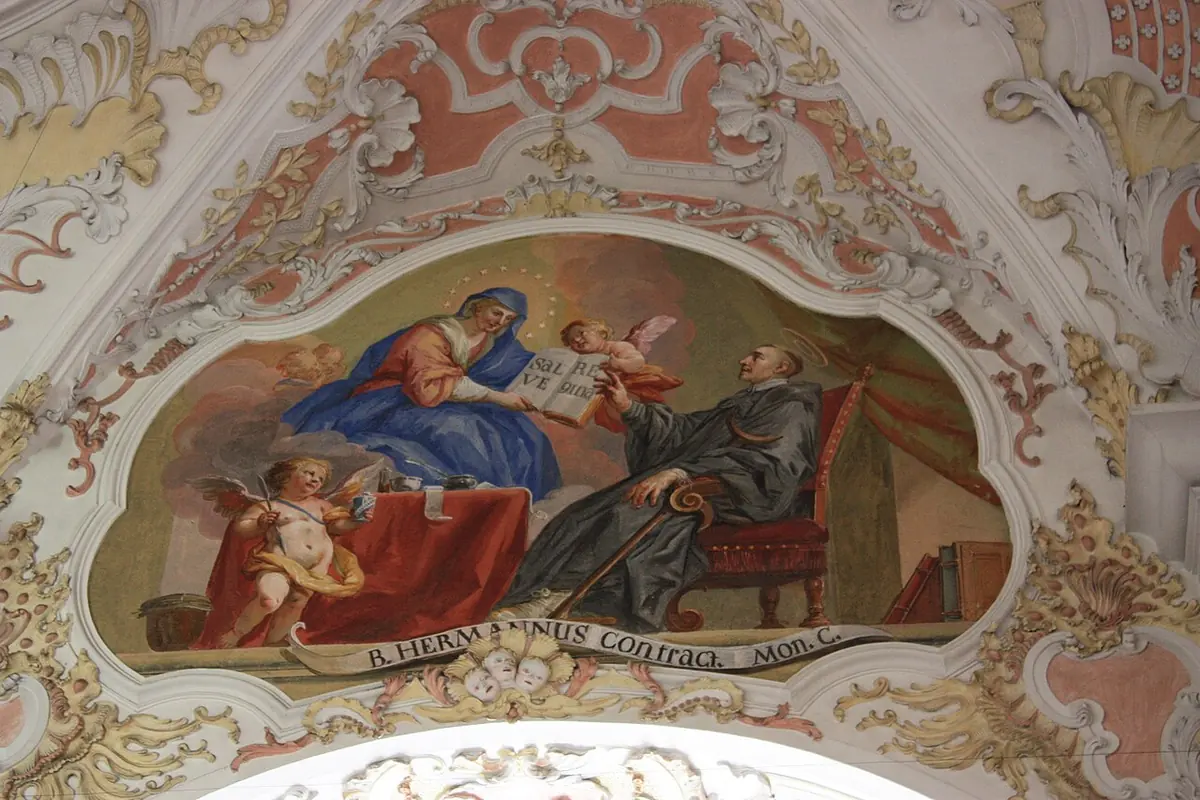 Pintura de techo en un marco de estuco de la Virgen María sentada sobre nubes entre ángeles, que se aparece a un monje de hábito negro sentado en una silla junto a unos libros