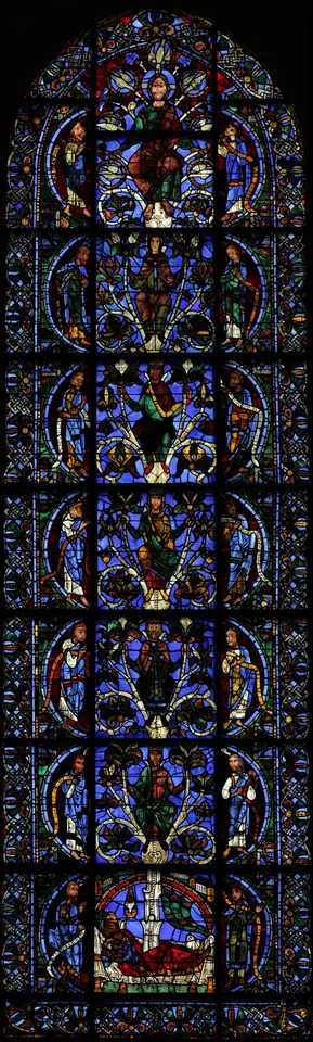 Tall narrow stained-glass window in deep blue and red, with a sleeping Jesse at the bottom and a line of crowned kings rising one above another to the Virgin and Christ at the top, prophets in half-circles on both sides