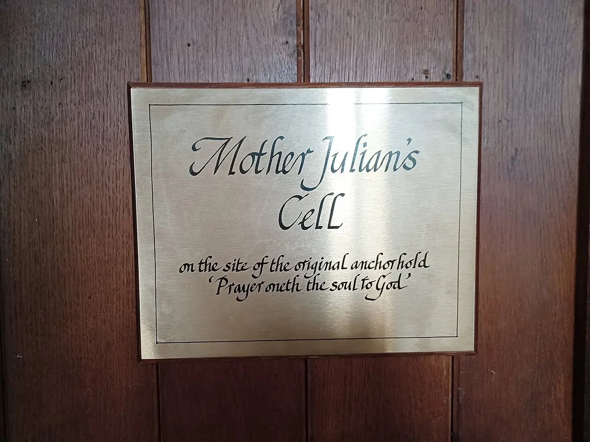 Brass plaque on a wooden door reading Mother Julian's Cell, on the site of the original anchorhold