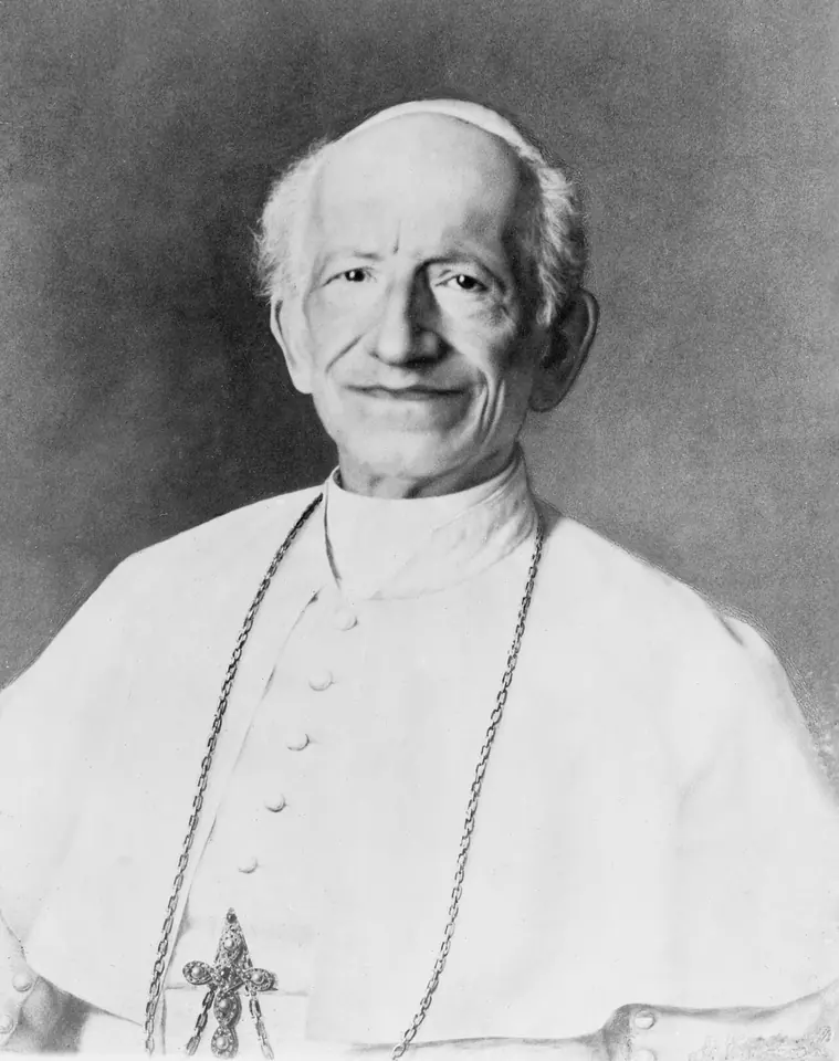 Black-and-white photograph of an elderly smiling pope in a white cassock and skullcap, with a pectoral cross
