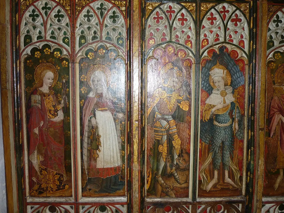 Painted panels of an English medieval rood screen under red and green Gothic tracery, with St. Zita in a long white apron holding a ring of keys and a purse, beside St. Apollonia with her pincers and two angels