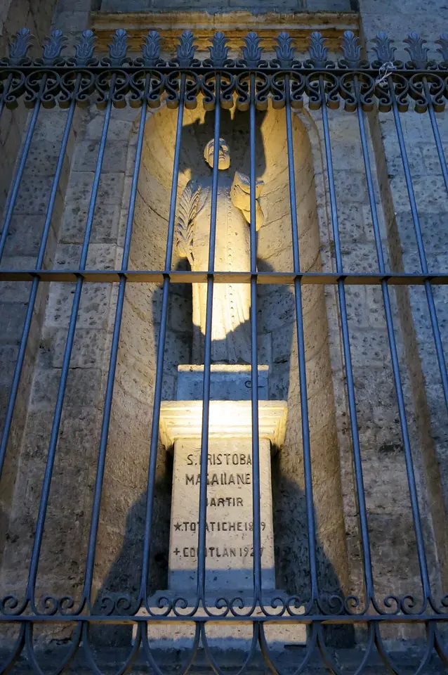 A stone niche behind an iron grille with a lit memorial inscribed with the name of St. Cristóbal Magallanes, martyr, Totatiche 1869, Colotlán 1927