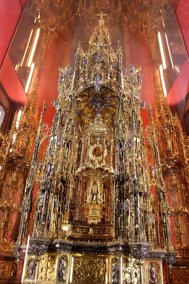 The towering Gothic silver-gilt custodia of Toledo Cathedral, a forest of pinnacles, arches and tiny statues around a small inner monstrance, lit against a red background