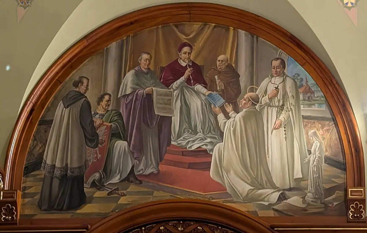 A half-moon mural of a kneeling priest in a white habit receiving a book from a seated pope in red, surrounded by clergy in a columned hall