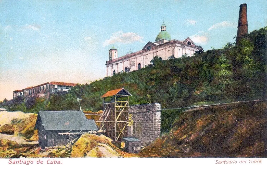 Hand-tinted postcard of the old domed sanctuary church on a green hillside above the copper mine workings of El Cobre, with a tall chimney