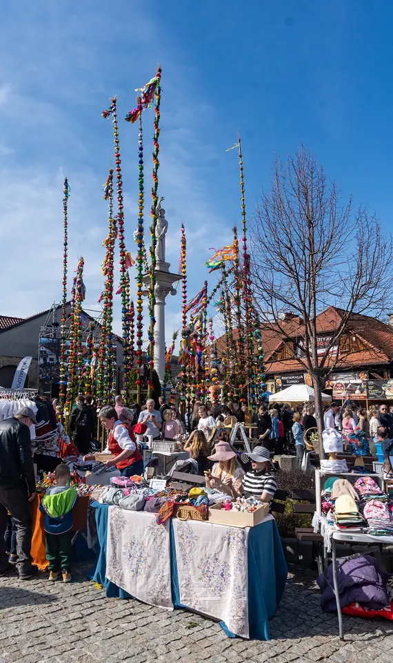 Palmas de Pascua polacas muy altas, hechas con varas, sauce, ramas verdes y flores de papel de colores, se alzan por encima de la gente en la plaza de un pueblo