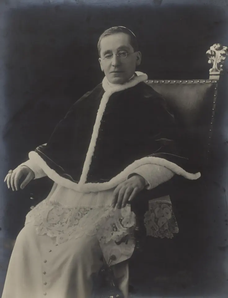 Black-and-white portrait photograph of Pope Benedict XV, a slight man with glasses, in a white cassock and skullcap with a pectoral cross