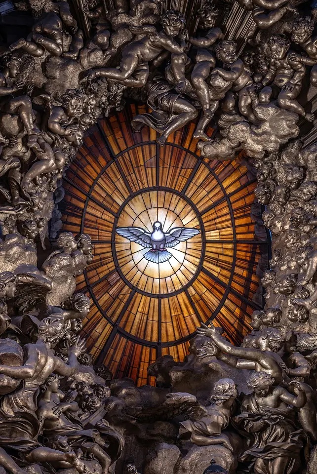 A white dove with outstretched wings in an oval golden window, surrounded by rays and gilded clouds and angels