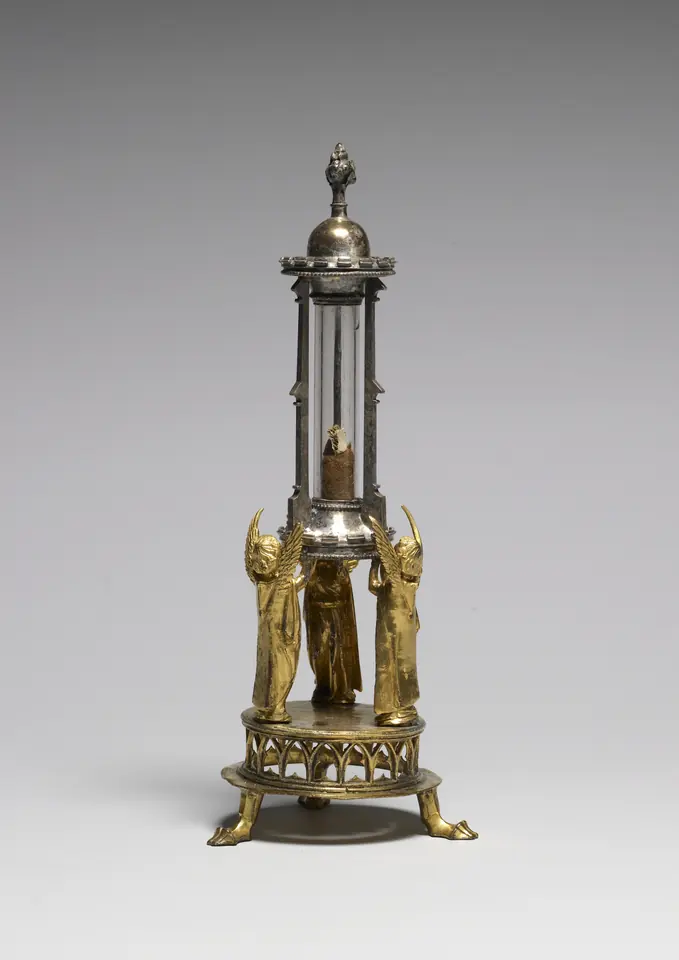 Gilded silver reliquary with three small angels holding up a glass cylinder that contains a wrapped fragment of bone