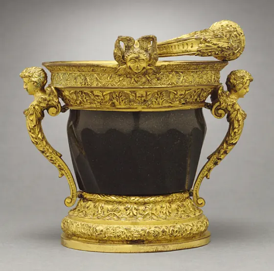A small dark green serpentine stone bucket with gilt bronze mounts, carved angel heads at the handles and an ornate gilt sprinkler resting across the top