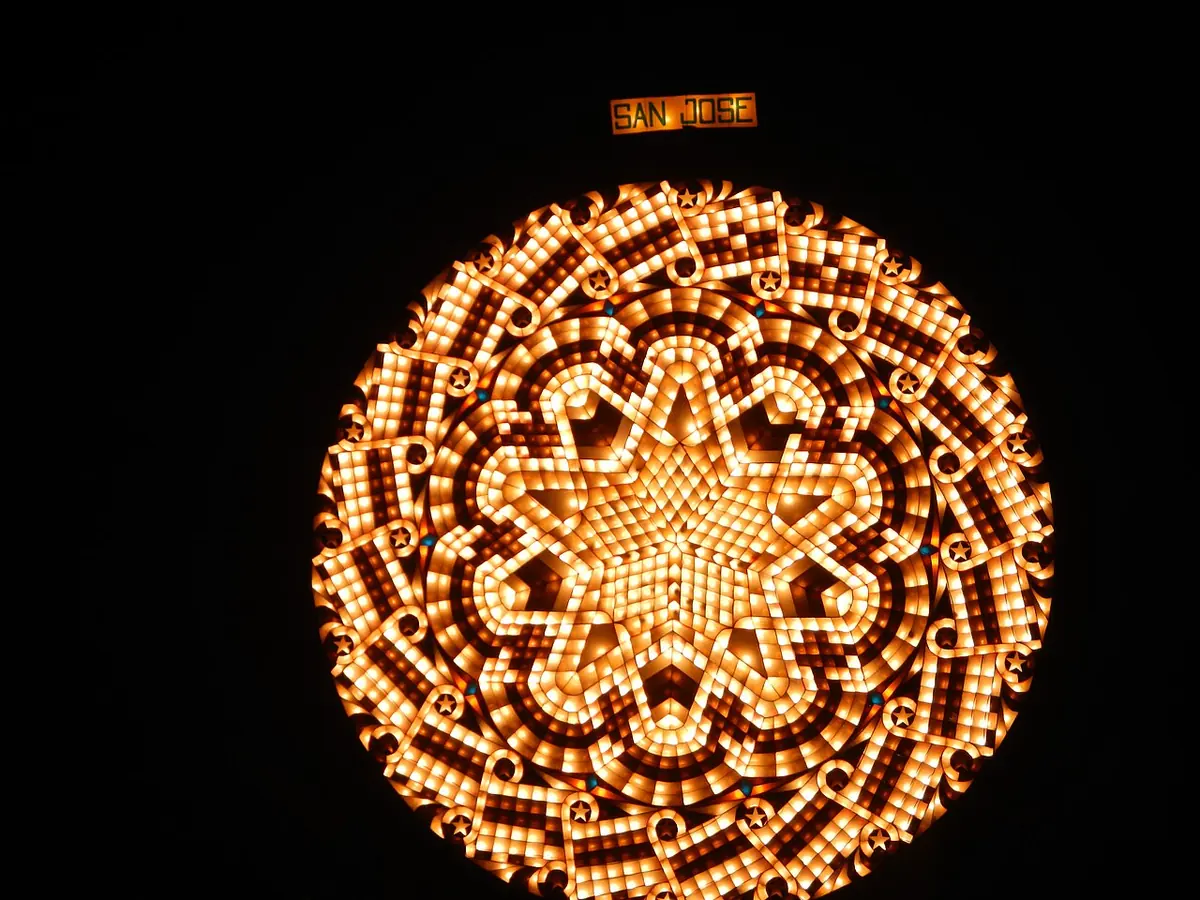 A huge round lantern made of hundreds of small golden lights arranged in petals around a central star, glowing against a black night sky