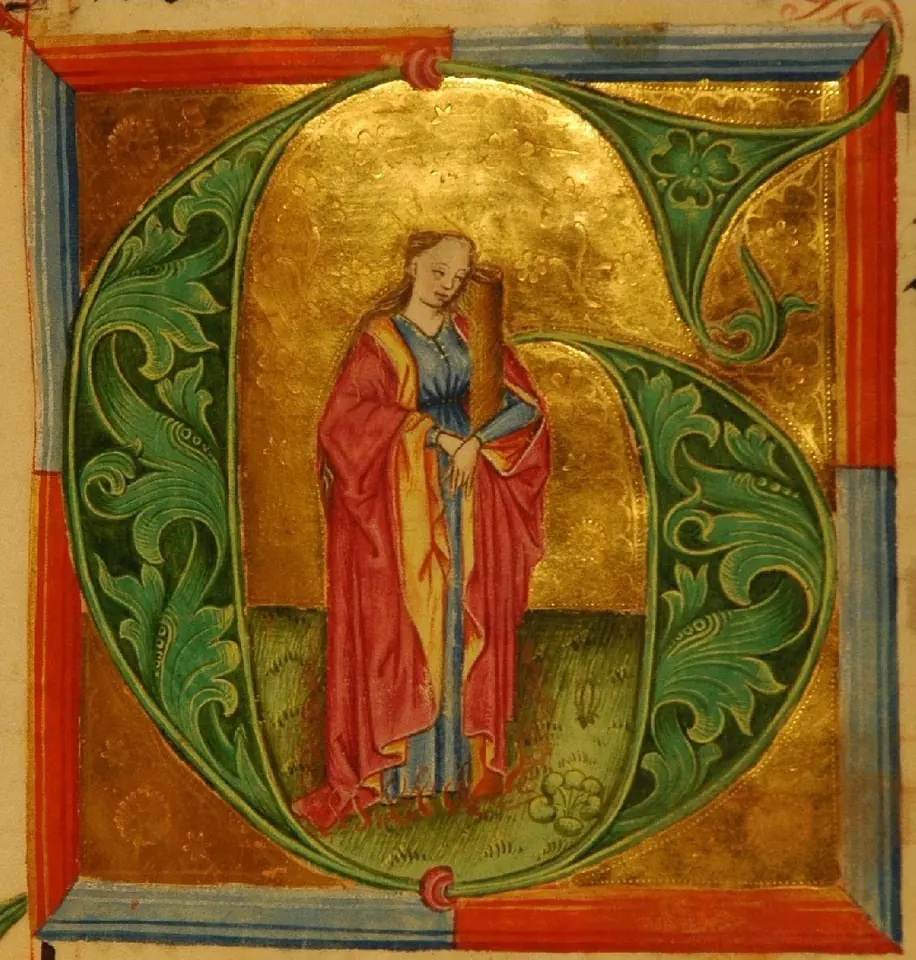 A large green and gold illuminated letter G framing St. Afra in a red cloak standing against a tree trunk