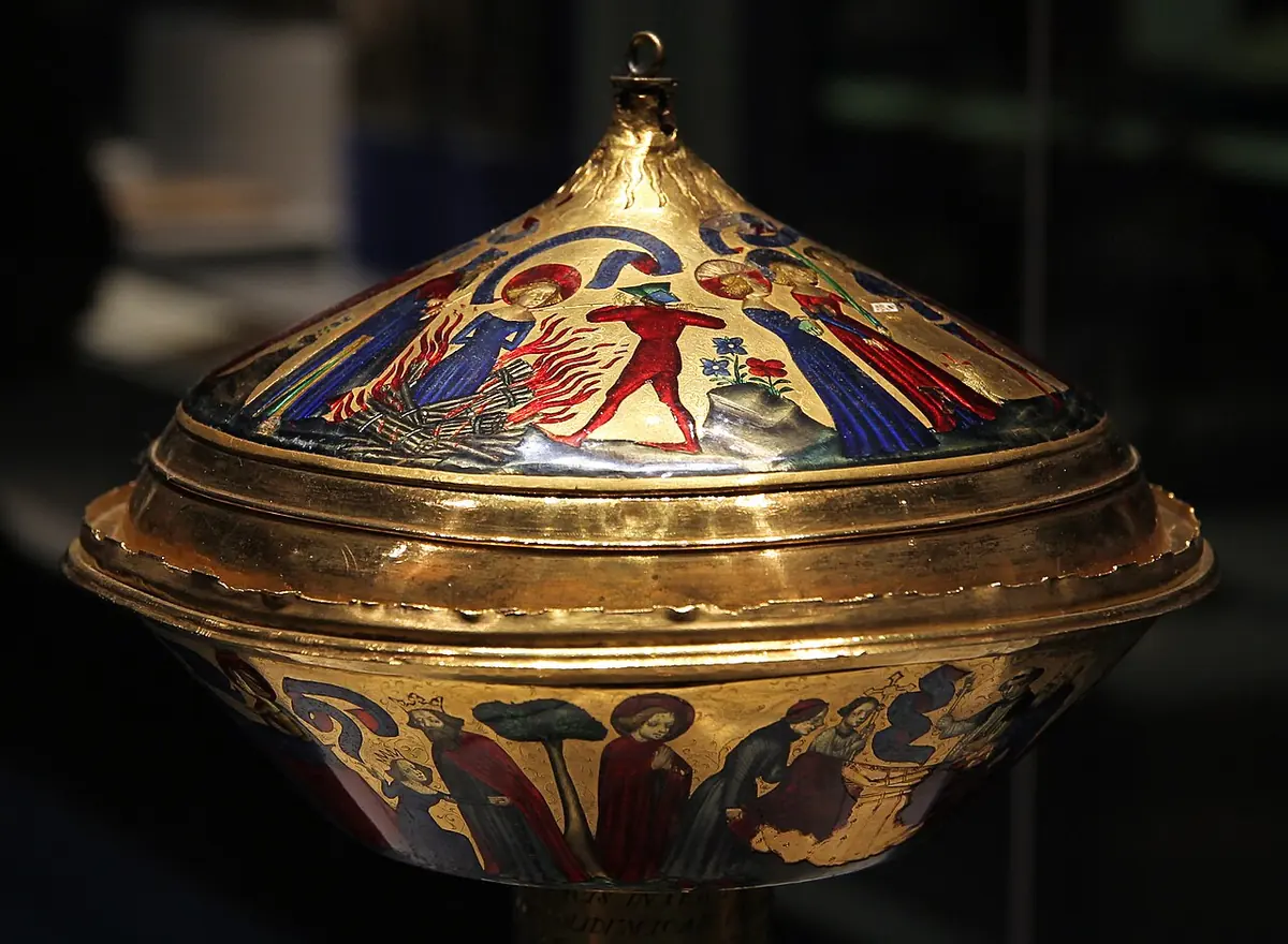 Gold lidded cup decorated with bright red and blue enamel figures, including a girl standing in flames between two men